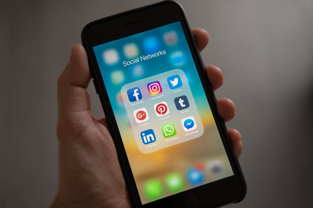 Topics 2 A smartphone displaying various social media icons held in a hand, showcasing modern communication apps.